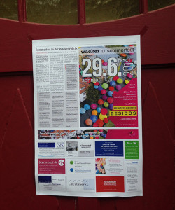 Ausdruck der Zeitungsseite zum Sommerfest auf dem roten Eingangstor in der Wackerfabrik